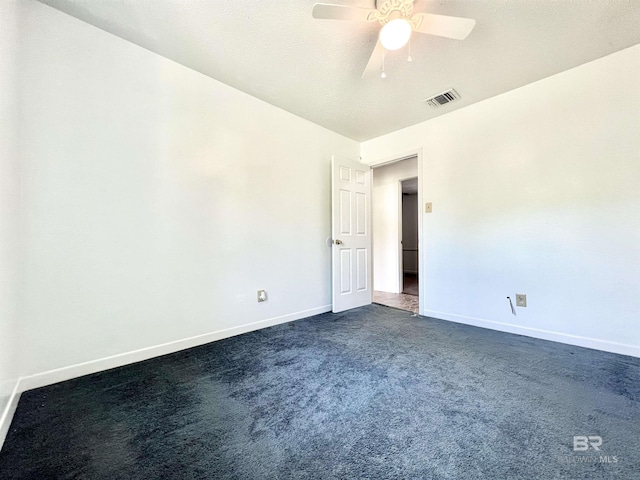 spare room with dark colored carpet, visible vents, baseboards, and a ceiling fan