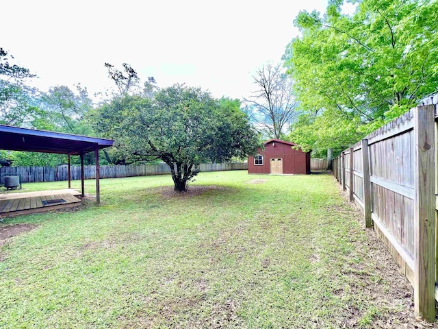 view of yard featuring a shed, a fenced backyard, a deck, and an outdoor structure