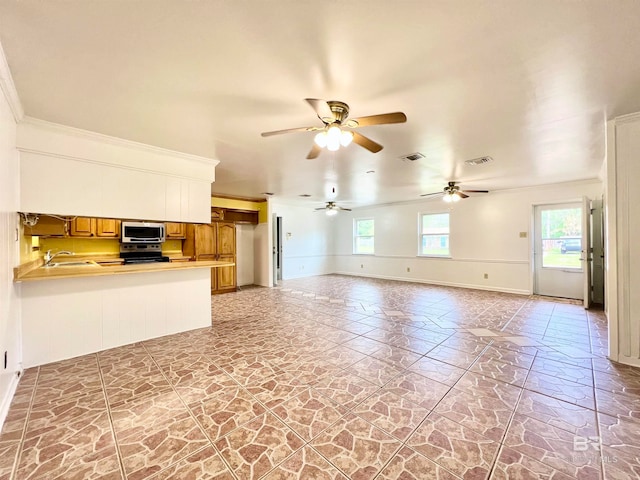 unfurnished living room featuring ceiling fan, crown molding, and sink