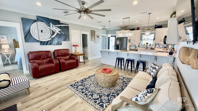 living room with ceiling fan, crown molding, and light hardwood / wood-style flooring