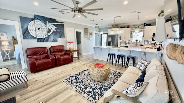 living room featuring crown molding, ceiling fan, and light wood-type flooring