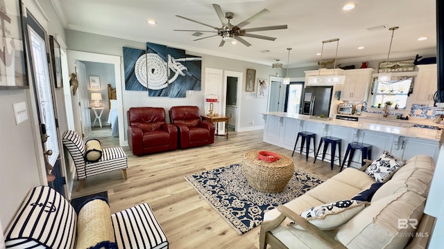 living room featuring ceiling fan, light wood-type flooring, and crown molding