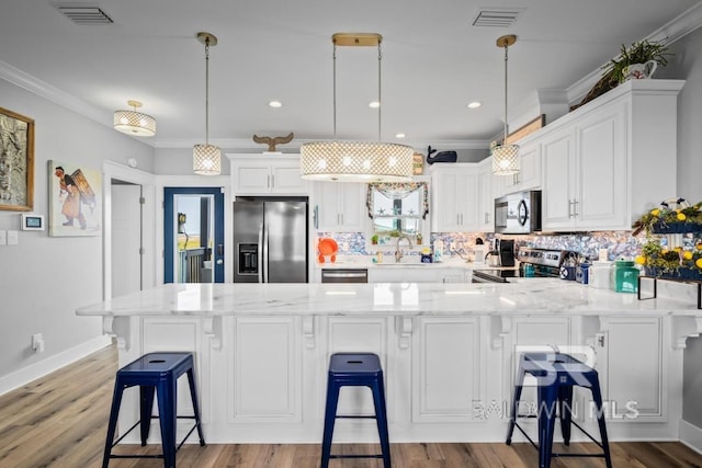 kitchen featuring stainless steel appliances, hanging light fixtures, tasteful backsplash, and light wood-type flooring