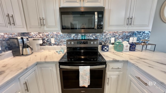 kitchen with tasteful backsplash, appliances with stainless steel finishes, light stone counters, and white cabinets