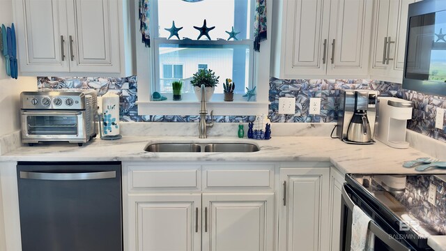 kitchen featuring white cabinetry, stainless steel appliances, light stone countertops, and sink