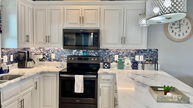 kitchen with light stone countertops, white cabinets, backsplash, and stainless steel appliances