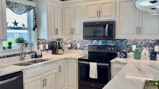 kitchen with white cabinetry, sink, light stone countertops, appliances with stainless steel finishes, and backsplash