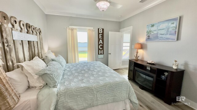 bedroom with light hardwood / wood-style floors, multiple windows, and ornamental molding