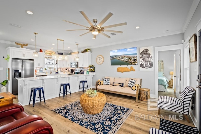 living room with crown molding, ceiling fan, and light hardwood / wood-style floors