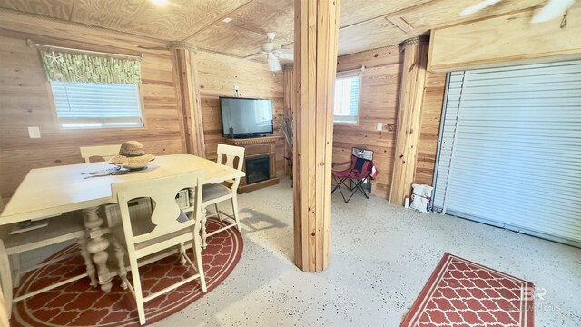 dining area featuring ceiling fan and wooden walls