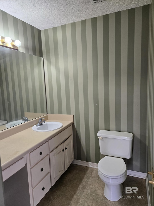 half bathroom featuring wallpapered walls, baseboards, toilet, a textured ceiling, and vanity