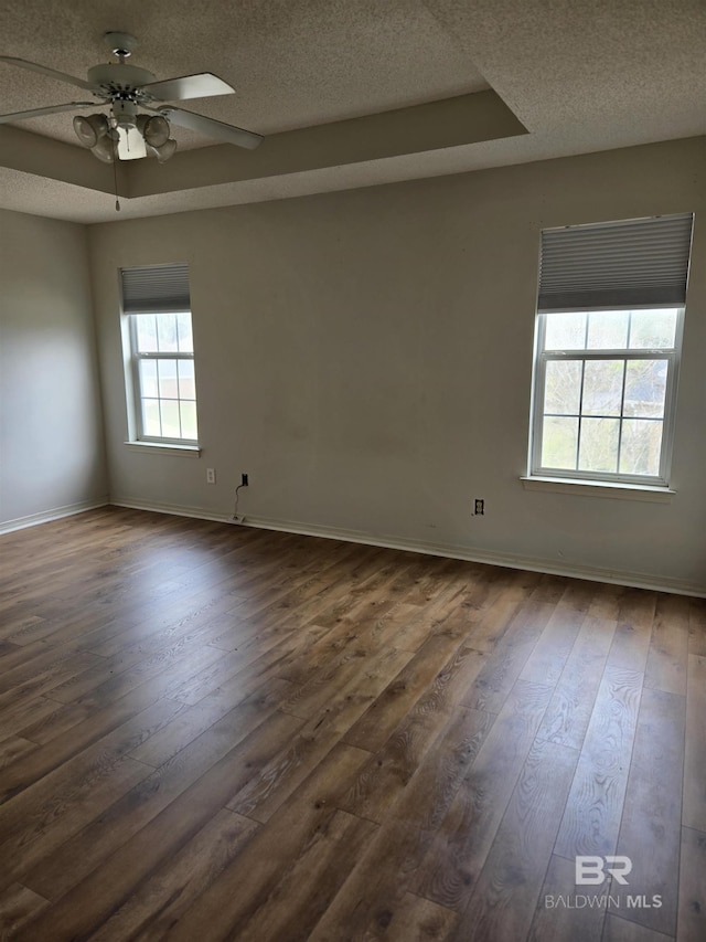 unfurnished room featuring a textured ceiling, ceiling fan, dark wood-style flooring, and baseboards