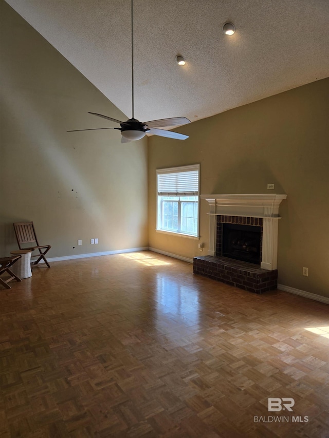 unfurnished living room featuring a fireplace, ceiling fan, a textured ceiling, high vaulted ceiling, and baseboards