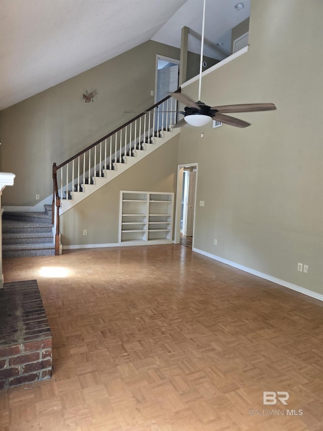 unfurnished living room with baseboards, a high ceiling, stairway, and ceiling fan