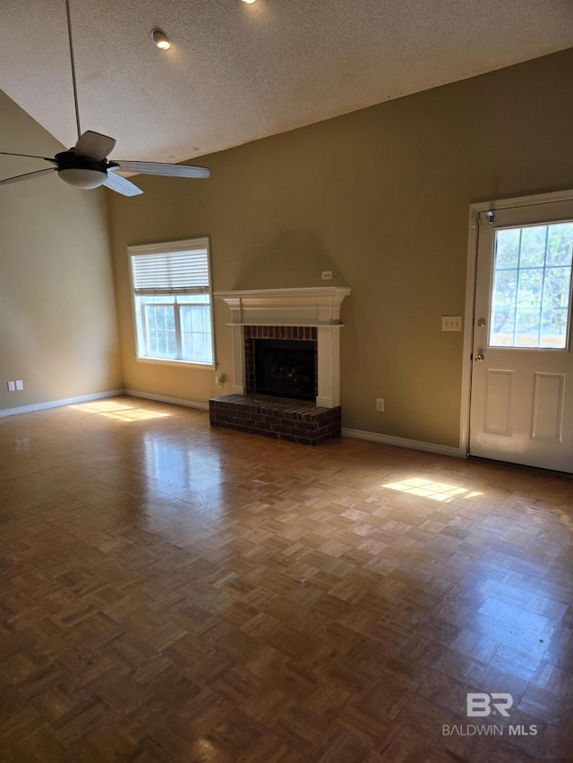 unfurnished living room with lofted ceiling, a brick fireplace, ceiling fan, and a textured ceiling