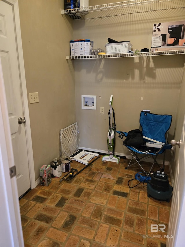 laundry room featuring hookup for a washing machine, baseboards, laundry area, and brick floor