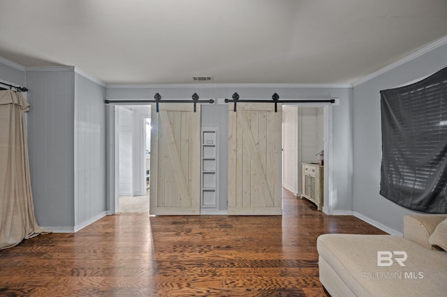living area featuring a barn door, ornamental molding, wood finished floors, and baseboards