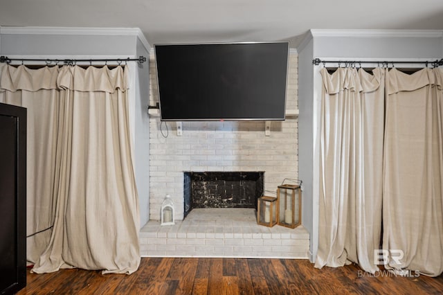 living area featuring ornamental molding, wood finished floors, and a brick fireplace