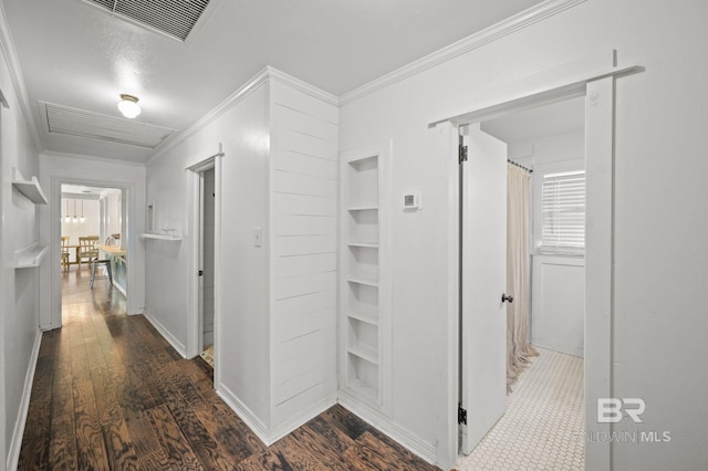 hall with dark wood-style flooring, crown molding, and baseboards