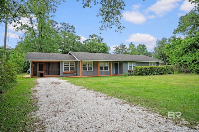 ranch-style home featuring a sunroom, gravel driveway, and a front lawn
