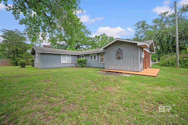 rear view of house with a lawn and board and batten siding