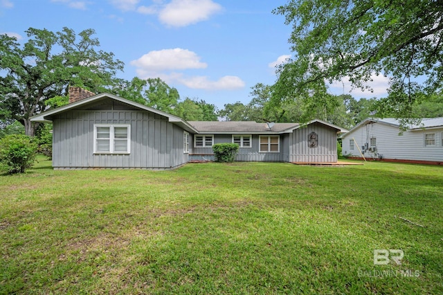 single story home featuring board and batten siding, a chimney, and a front yard