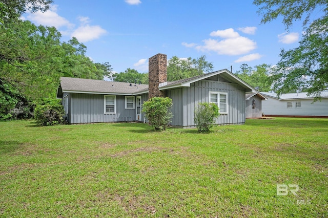 rear view of property with a chimney, board and batten siding, and a lawn