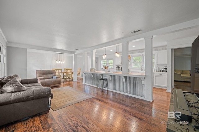 living room featuring light wood finished floors, ornate columns, and ornamental molding