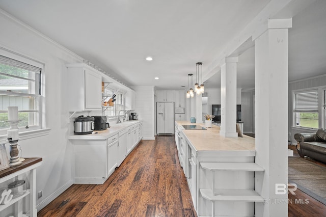 kitchen with white fridge with ice dispenser, a sink, light countertops, white cabinets, and crown molding