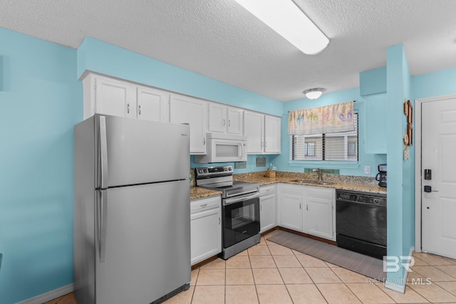 930 W Beach Blvd Unit 108, Gulf Shores, AL 36542 - kitchen featuring stainless steel appliances, a textured ceiling, white cabinets, light stone countertops, and light tile patterned floors