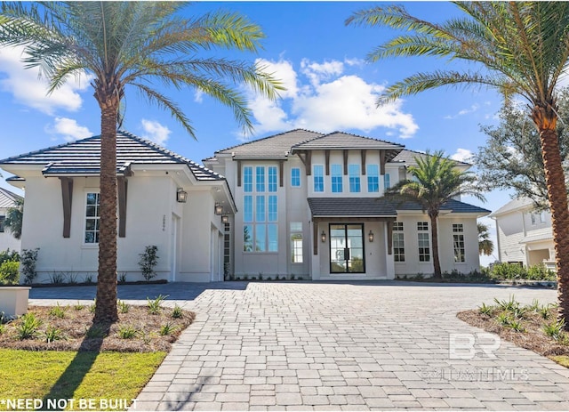 view of front facade with decorative driveway, a tiled roof, and stucco siding