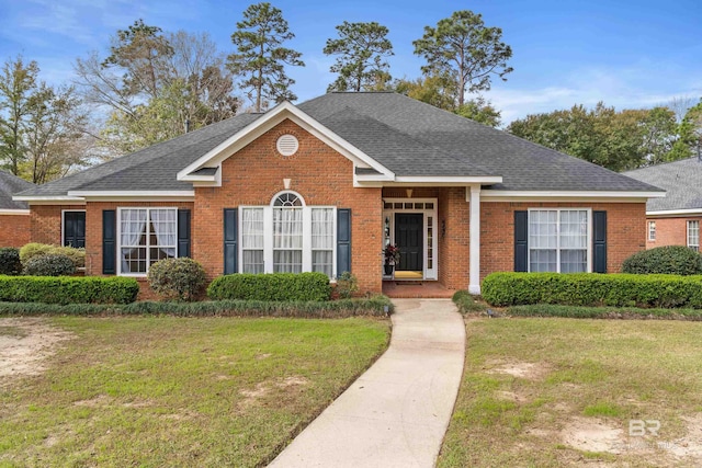 view of front of home featuring brick siding, roof with shingles, and a front yard