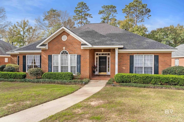 view of front of home featuring a front yard, brick siding, and a shingled roof