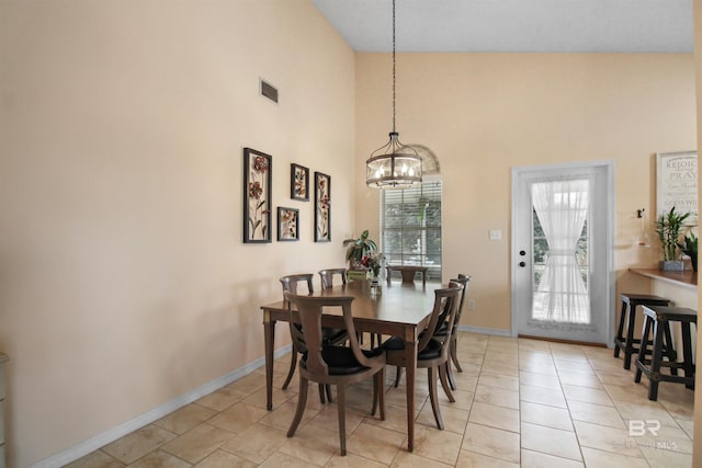 dining area with a high ceiling, light tile patterned floors, and a notable chandelier