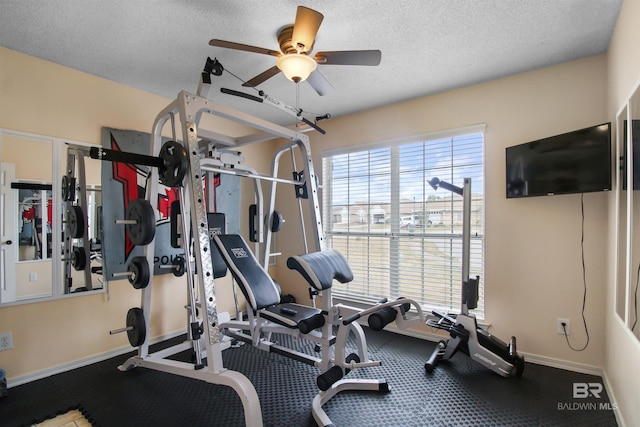 exercise room with ceiling fan and a textured ceiling