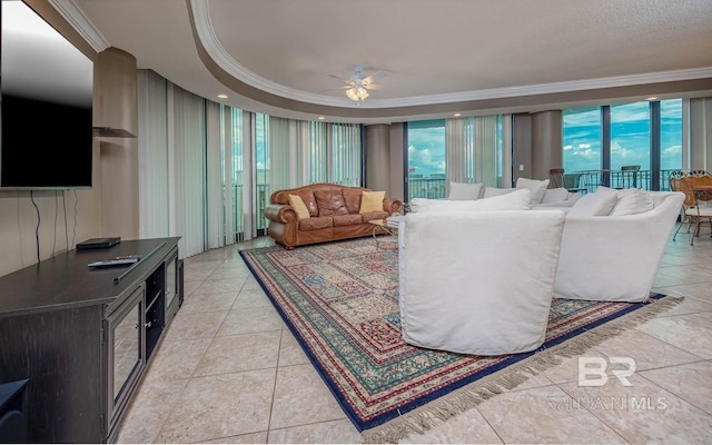 tiled living room with a raised ceiling, ceiling fan, and ornamental molding