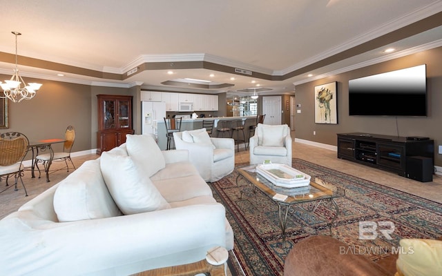 living room featuring a tray ceiling, crown molding, and a chandelier