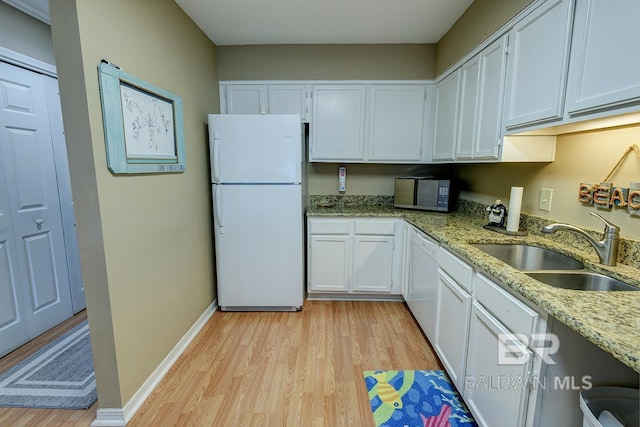 kitchen featuring sink, white appliances, light wood-type flooring, and white cabinetry