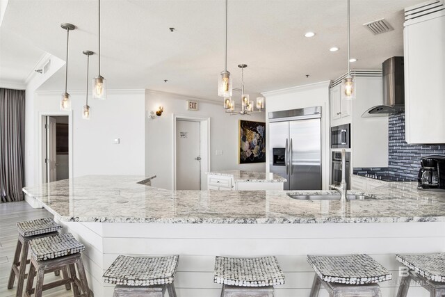 825 W Beach Blvd Unit 10, Gulf Shores, AL 36542 - kitchen featuring built in appliances, wall chimney exhaust hood, ornamental molding, and visible vents