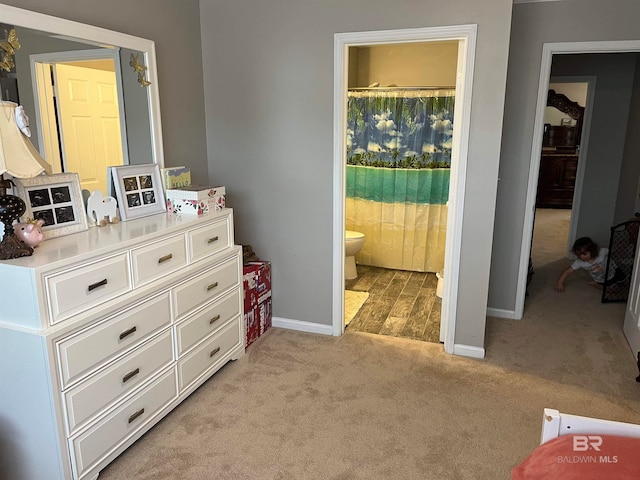 bedroom featuring connected bathroom and light carpet