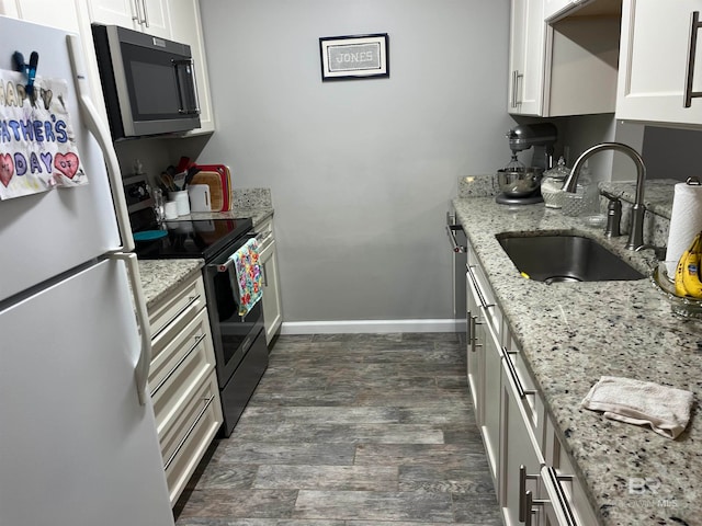 kitchen featuring dark hardwood / wood-style floors, light stone countertops, stainless steel appliances, sink, and white cabinets