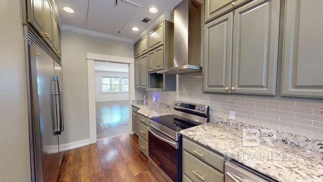 kitchen featuring dark wood-type flooring, crown molding, wall chimney exhaust hood, light stone counters, and stainless steel appliances