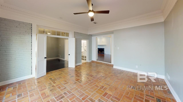 spare room featuring ceiling fan, ornamental molding, and a fireplace