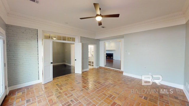 spare room featuring ceiling fan, ornamental molding, and a fireplace