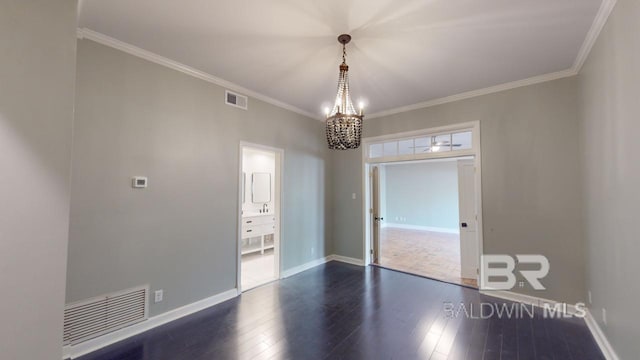 spare room featuring ornamental molding, dark wood-type flooring, and a notable chandelier