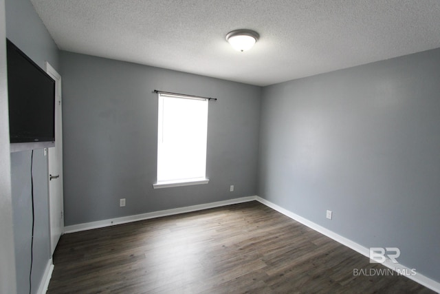 spare room with dark wood-type flooring and a textured ceiling