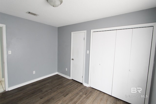 unfurnished bedroom featuring a closet and dark hardwood / wood-style floors