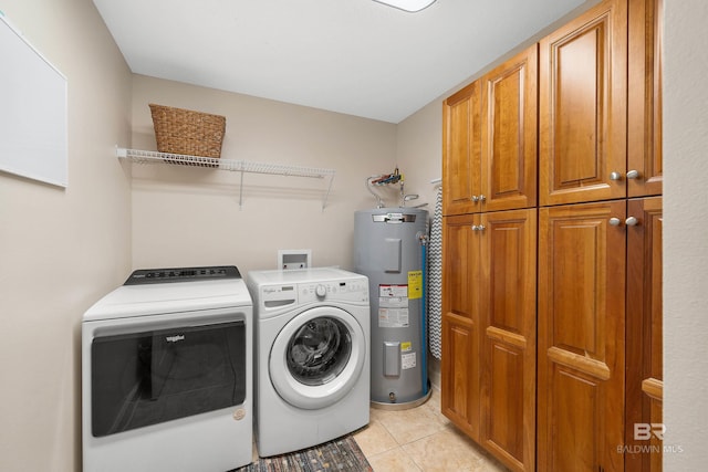 laundry room featuring cabinets, light tile patterned floors, washer and clothes dryer, and water heater