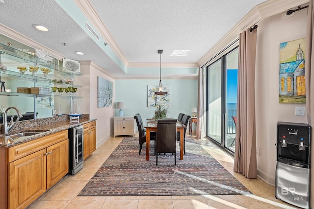 kitchen featuring dark stone counters, a textured ceiling, beverage cooler, crown molding, and sink