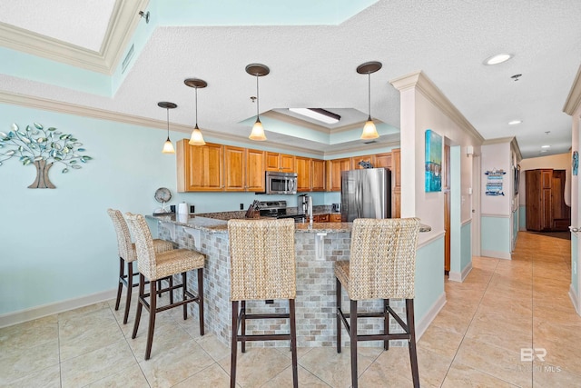 kitchen with kitchen peninsula, light stone counters, stainless steel appliances, and ornamental molding